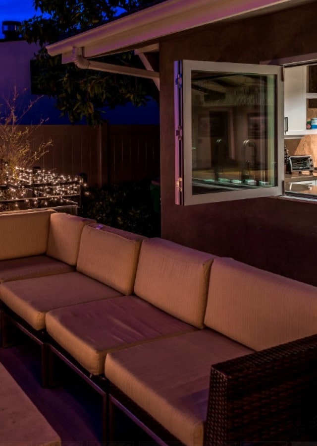 Outdoor patio with bi-fold doors opened to reveal a modern kitchen, in the twilight ambiance of Orange County.