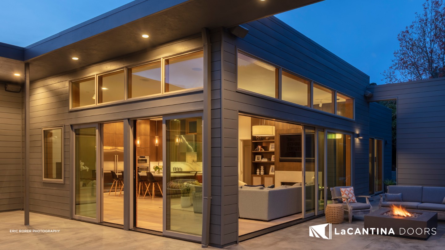 Twilight ambiance outside a modern home with La Cantina folding doors open to a cozy interior in Orange County.